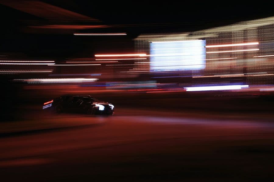 Car at night blurred by speed, red and orange light streaks